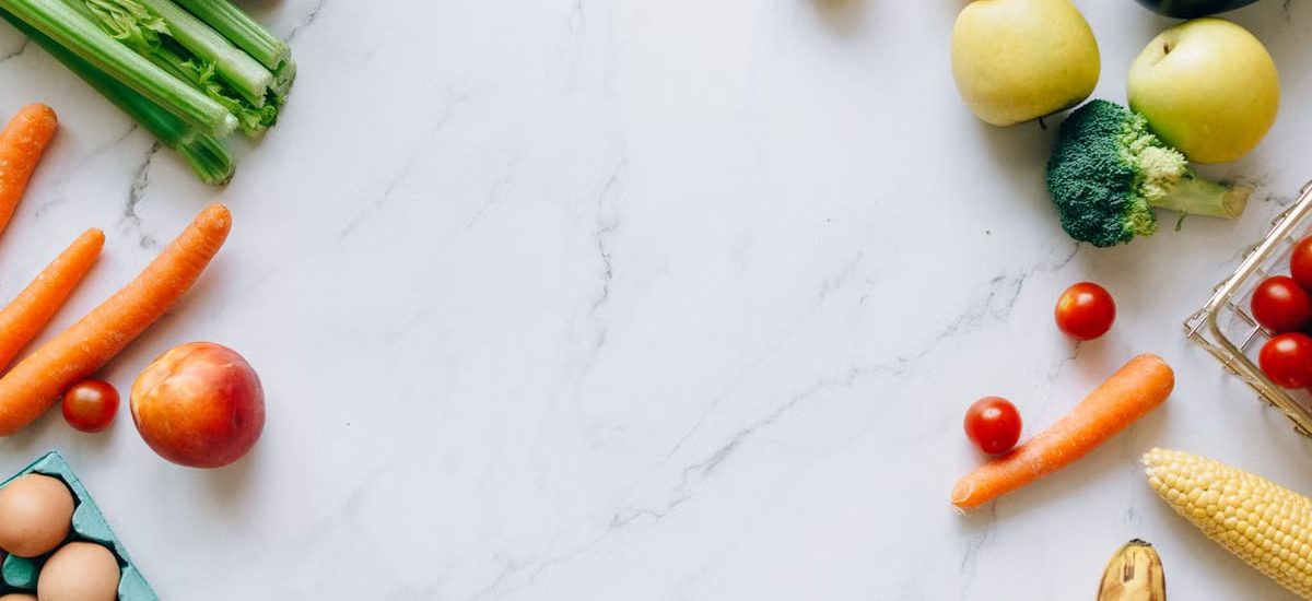 An assortment of fresh fruits and vegetables on a marble background, perfect for healthy lifestyle concepts.